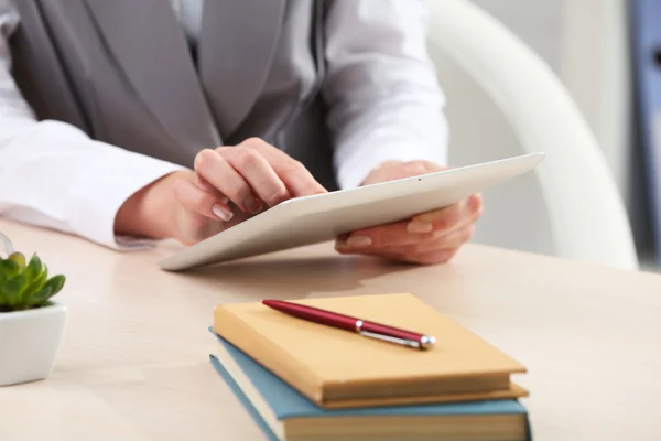 Woman using digital tablet on workplace close up