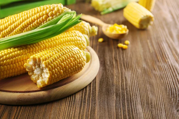 Ripe corn on cutting board on wooden background