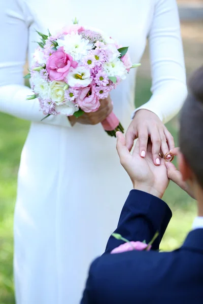 Groom wears ring bride outdoors