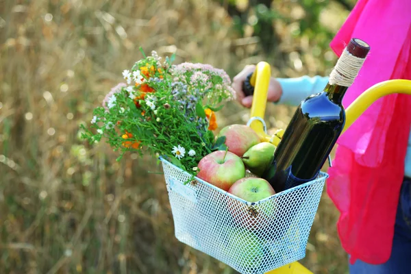 Young woman driving bike with basket of fresh foodstuffs, close-up