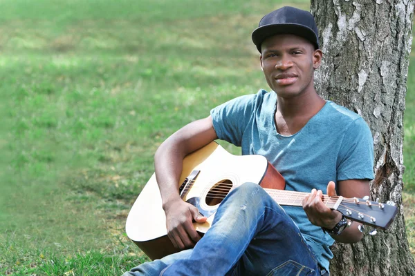 Man with guitar sitting in park