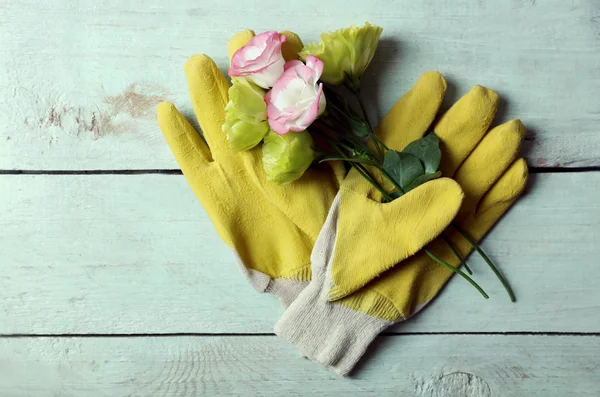 Pretty composition of blossom and gardener\'s gloves on light-blue wooden background