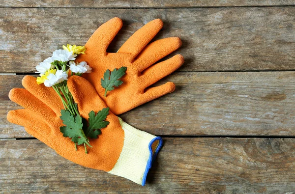 Beautiful composition of flower and garden gloves on wooden background