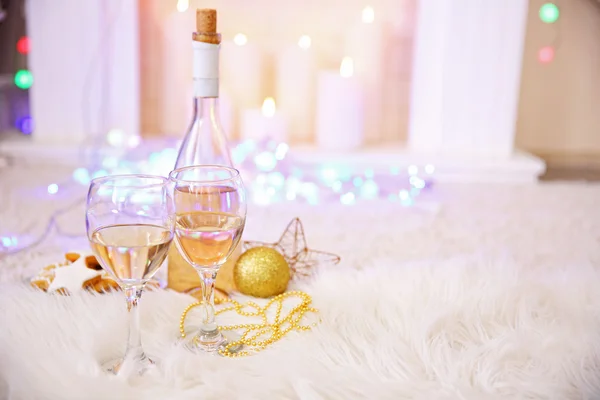 Bottle and glasses of wine with Christmas decor against colorful bokeh lights background
