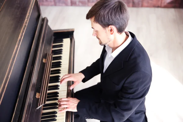 Man in black suit plays piano in the class