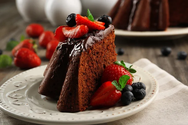Piece of chocolate cake with berries in plate on table, closeup