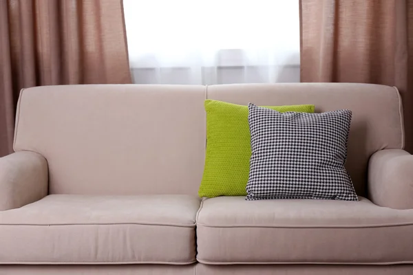 Comfortable sofa with pillows in the room, close up