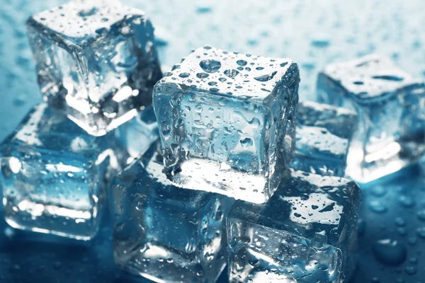 Melting ice cubes are in a row with drops around, close up