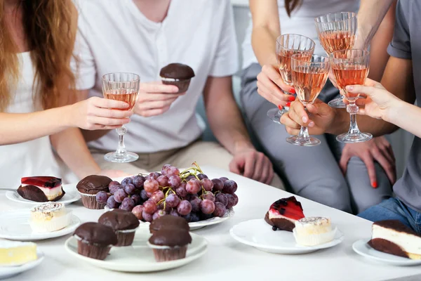 Friends hands with glasses of wine and desserts, close up