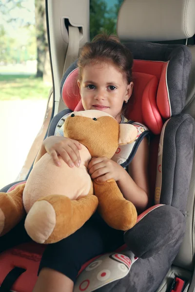 Little girl holds bear in the car