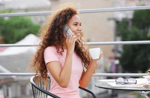 Woman speaking by cellphone and drinking coffee