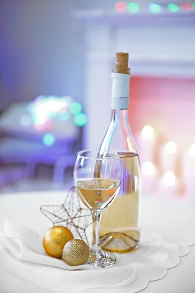 Bottle and glass of wine with Christmas decor against colorful bokeh lights background