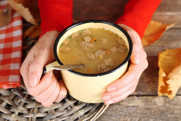 Hands holding mug of soup