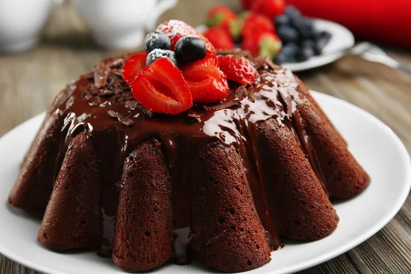 Delicious chocolate cake with berries in plate on table, closeup