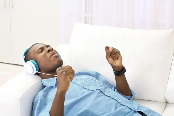 Handsome African American man with headphones lying on sofa close up