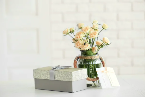 Big beautiful gift box with bouquet of flowers on the table in front of brick wall, close up