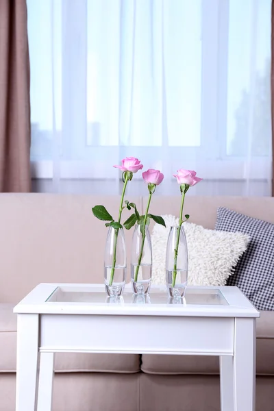 Sofa with beautiful pillows and focused vase with flowers on the table in front of it in the room