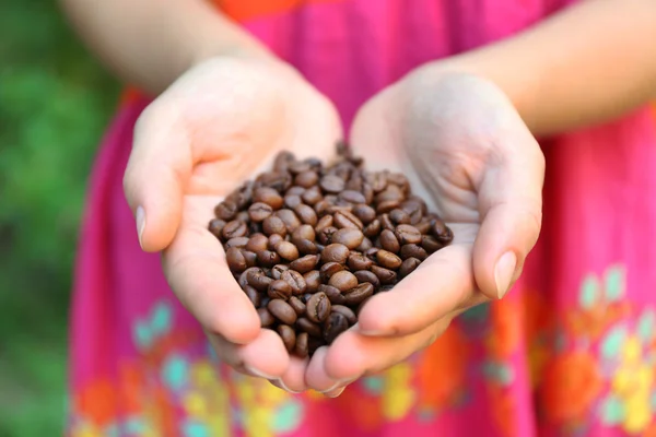 Woman holds in hands roasted coffee beans