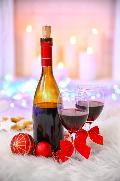 Bottle and glasses of wine with Christmas decor against colorful bokeh lights background