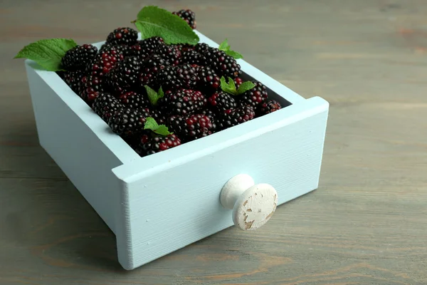 Heap of sweet blackberries with mint in box on table close up