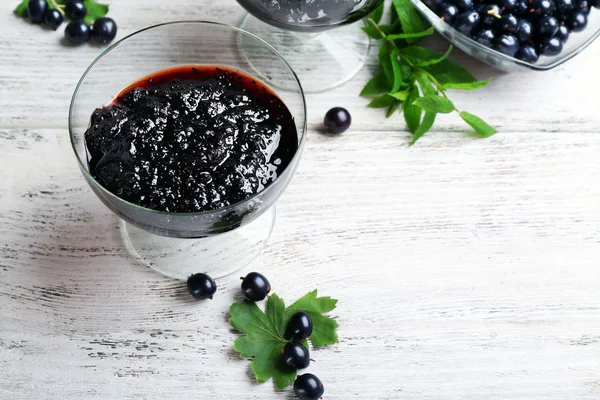 Tasty currant jam with berries on table close up