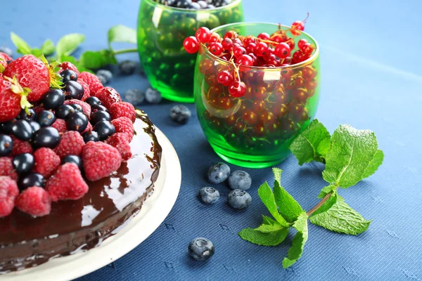 Delicious chocolate cake with summer berries on blue tablecloth, closeup