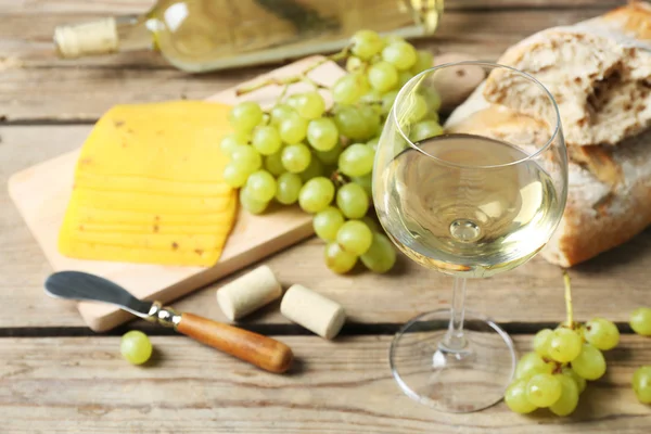 Still life of wine, grape, cheese and bread on rustic wooden background