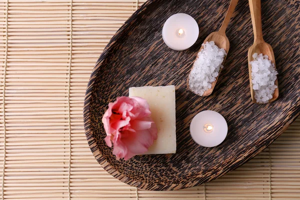 Spa composition of candles, soap, sea salt and flower on bamboo background