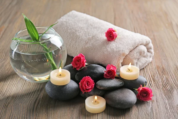 Spa composition of candles, flowers and stones on brown wooden background