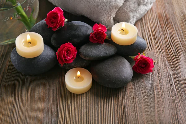 Spa composition of candles, flowers and stones on brown wooden background