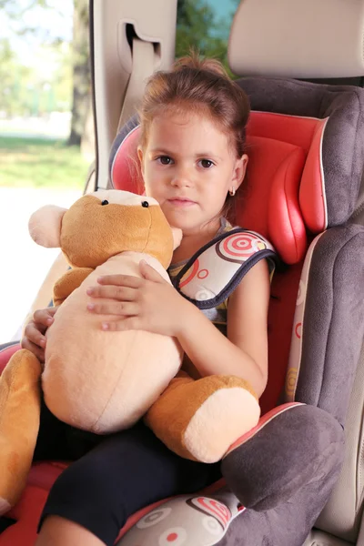 Little girl holds bear in the car