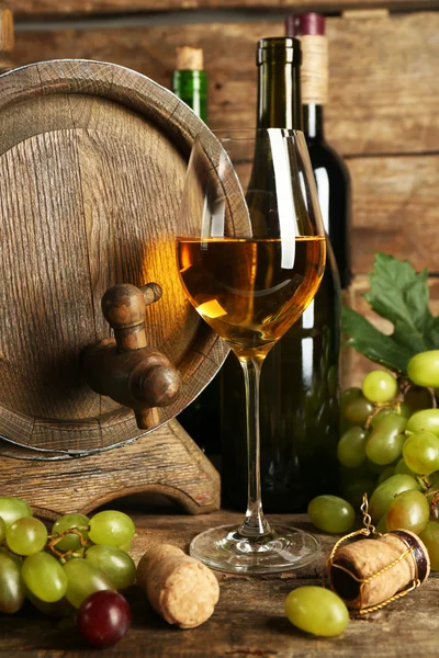 White and red grape with wine bottle near barrel on wooden background