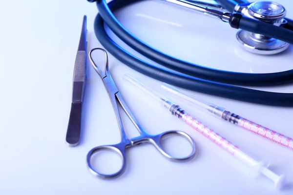 Stethoscope and surgery instruments on white background, close up