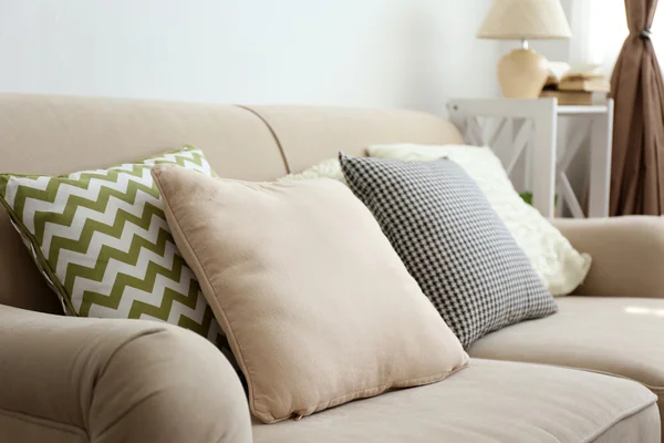 Comfortable sofa with pillows in the room, close up