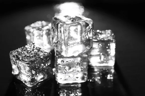 Shining ice cubes on dark liquid background