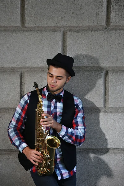 Young handsome man plays saxophone