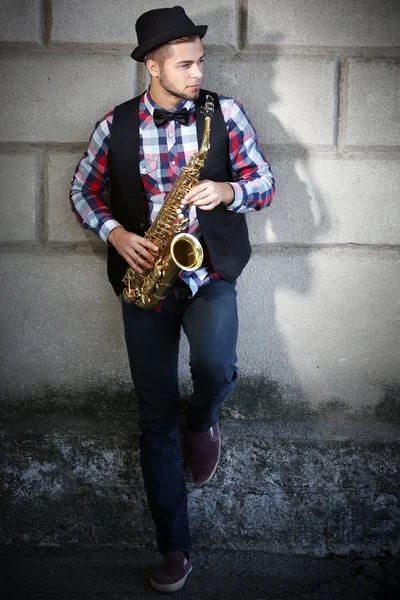 Young handsome man plays saxophone