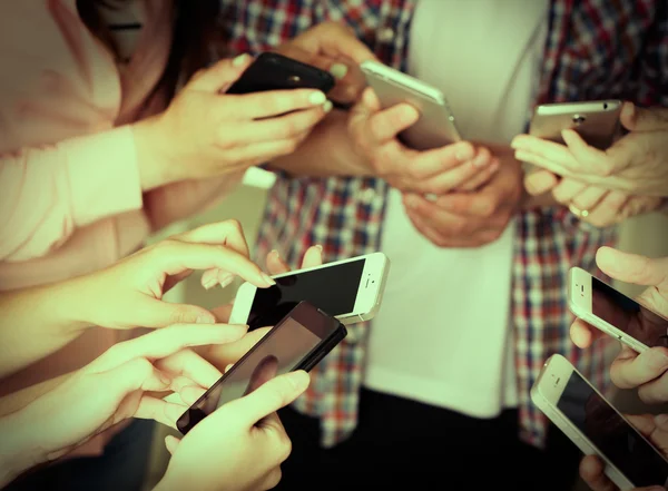 Many hands holding mobile phones close up