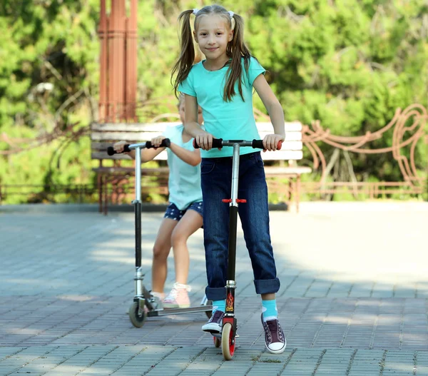 Small girls riding on scooters