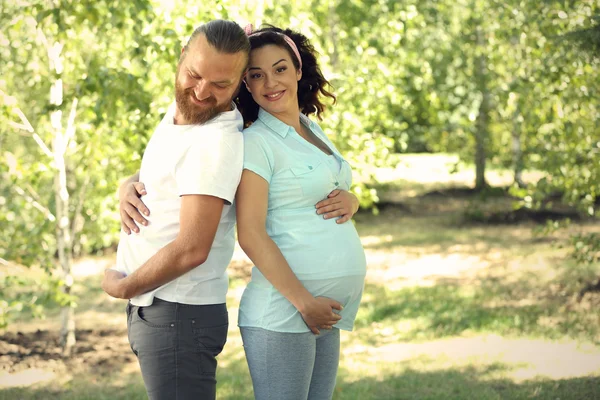 Happy family waiting for baby\'s birth have fun in the park