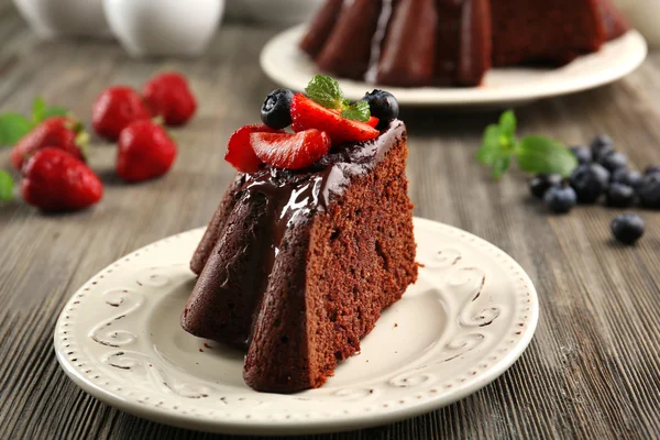 Piece of chocolate cake with berries in plate on table, closeup