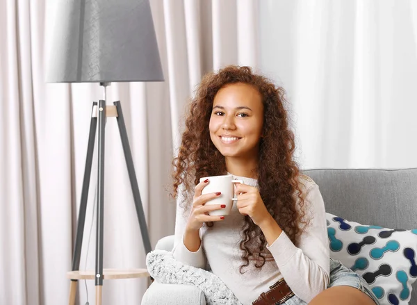 Young beautiful woman drinking coffee on sofa in the room