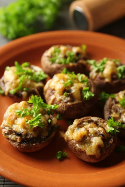 Stuffed mushrooms on plate, on table background