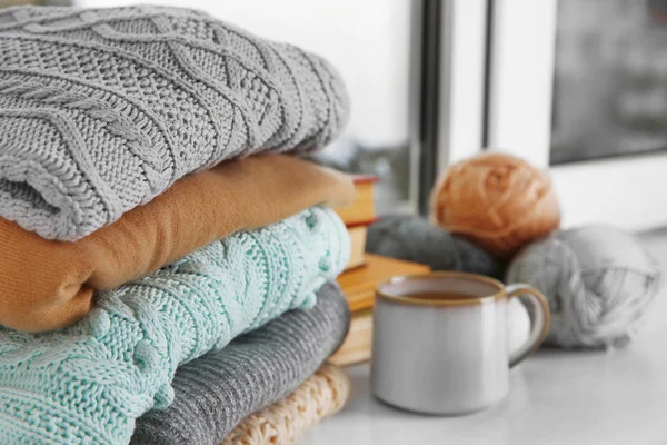 Mug of tea and warm knitted clothes in a room