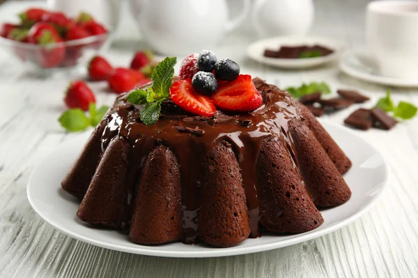Delicious chocolate cake with berries in plate on table, closeup
