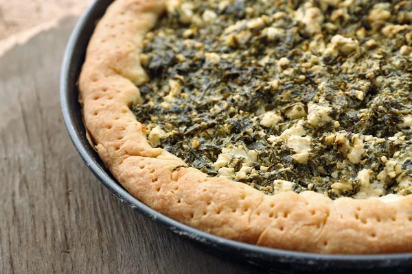 Open pie with spinach on wooden table close up