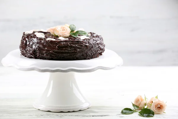 Chocolate cake decorated with flowers on white wooden table