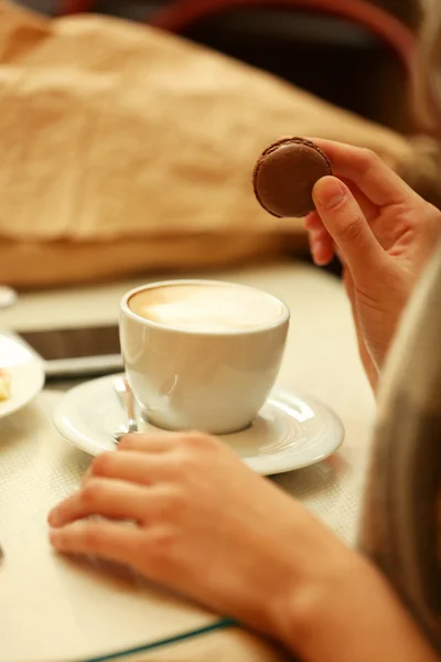 Woman with a cup of coffee and biscuit in cafe