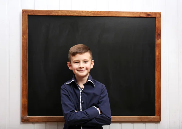 Cute boy posing at clean blackboard