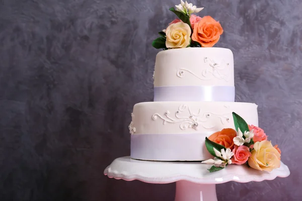 White wedding cake decorated with flowers on grey background